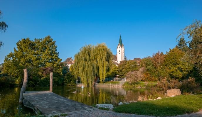 Stadtgarten mit Steg und Weiher. Im Hintergrund die Stadtkirche.