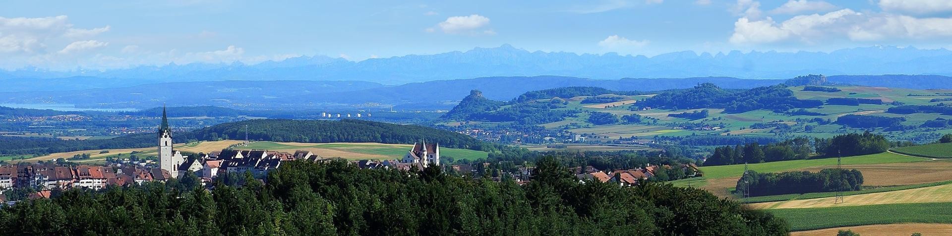 Engen inmitten einer grünen Landschaft und im Hintergrund das Alpenpanorama