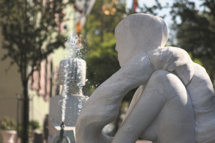 Ein Wasserstrahl aus dem Vorstadtbrunnen spritzt auf eine weiße Skulptur