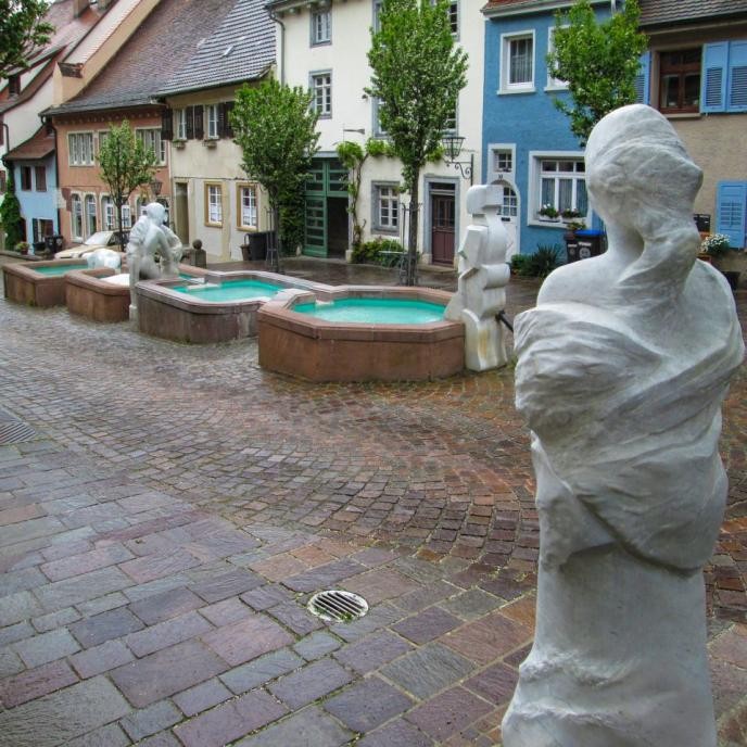 Langgezogener Brunnen mit Skulpturen in der Altstadt