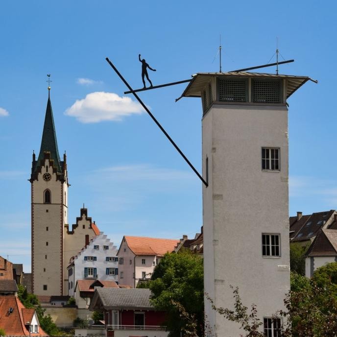 Balancierende Person auf einem Turm am Feuerwehrhaus