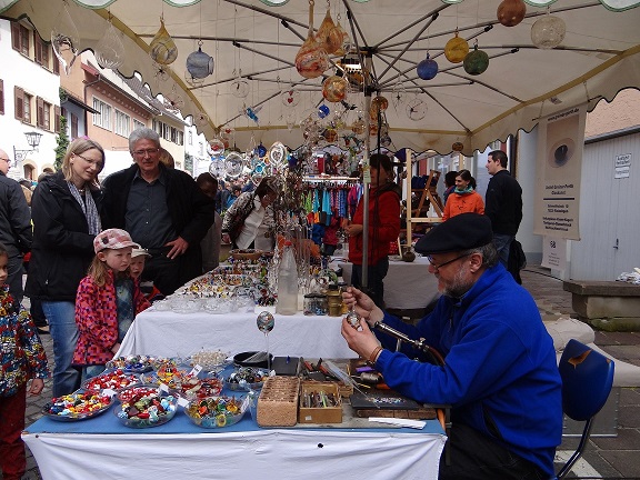 Interessiert Besucher beobachten einen Kunstahandwerker bei der Arbeit